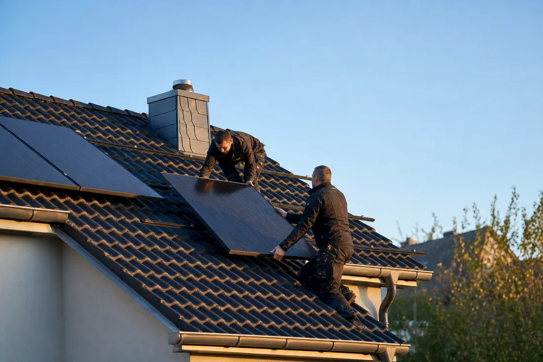 Installateure montieren Photovoltaikmodule auf dem Dach eines Hauses in Luxemburg